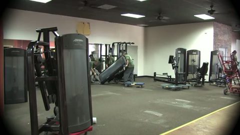 moving crew tilting a gym strength machine onto a furniture dolly