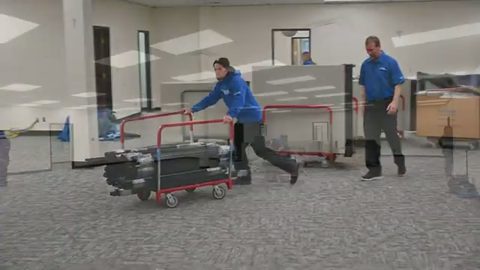 mover pushing a cart loaded with cubicle rails across an office, face visible